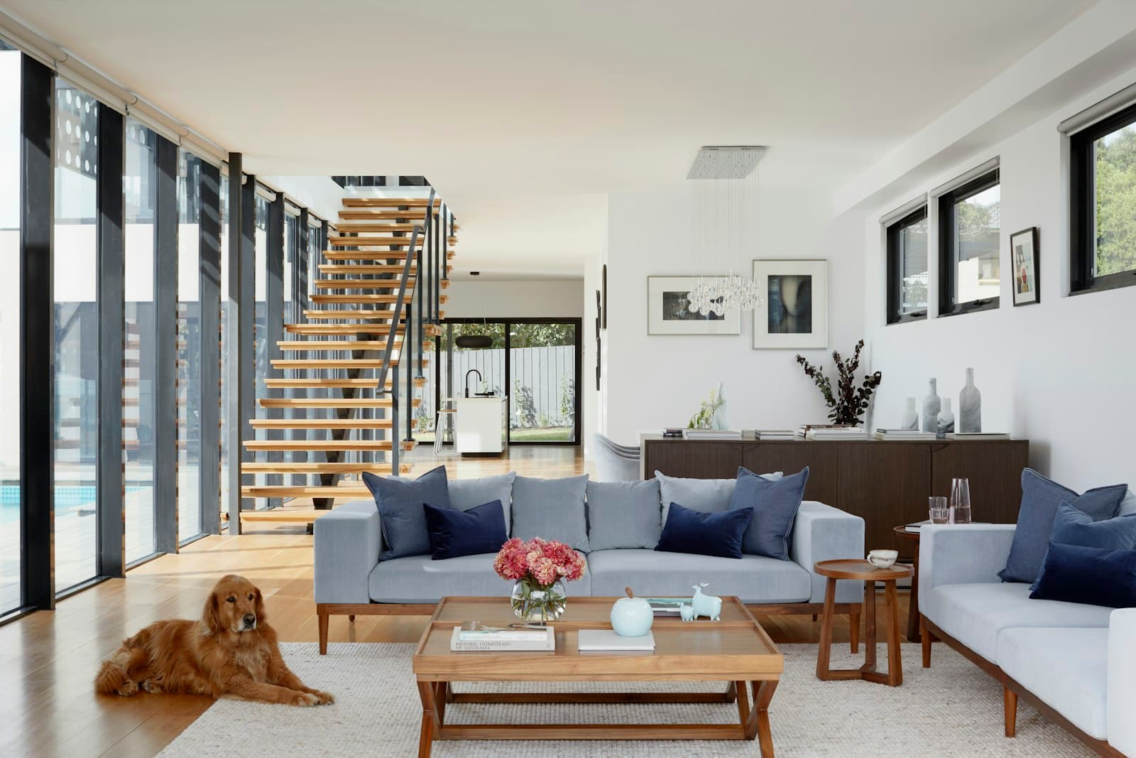 Open-plan living space with a floating staircase and floor-to-ceiling windows